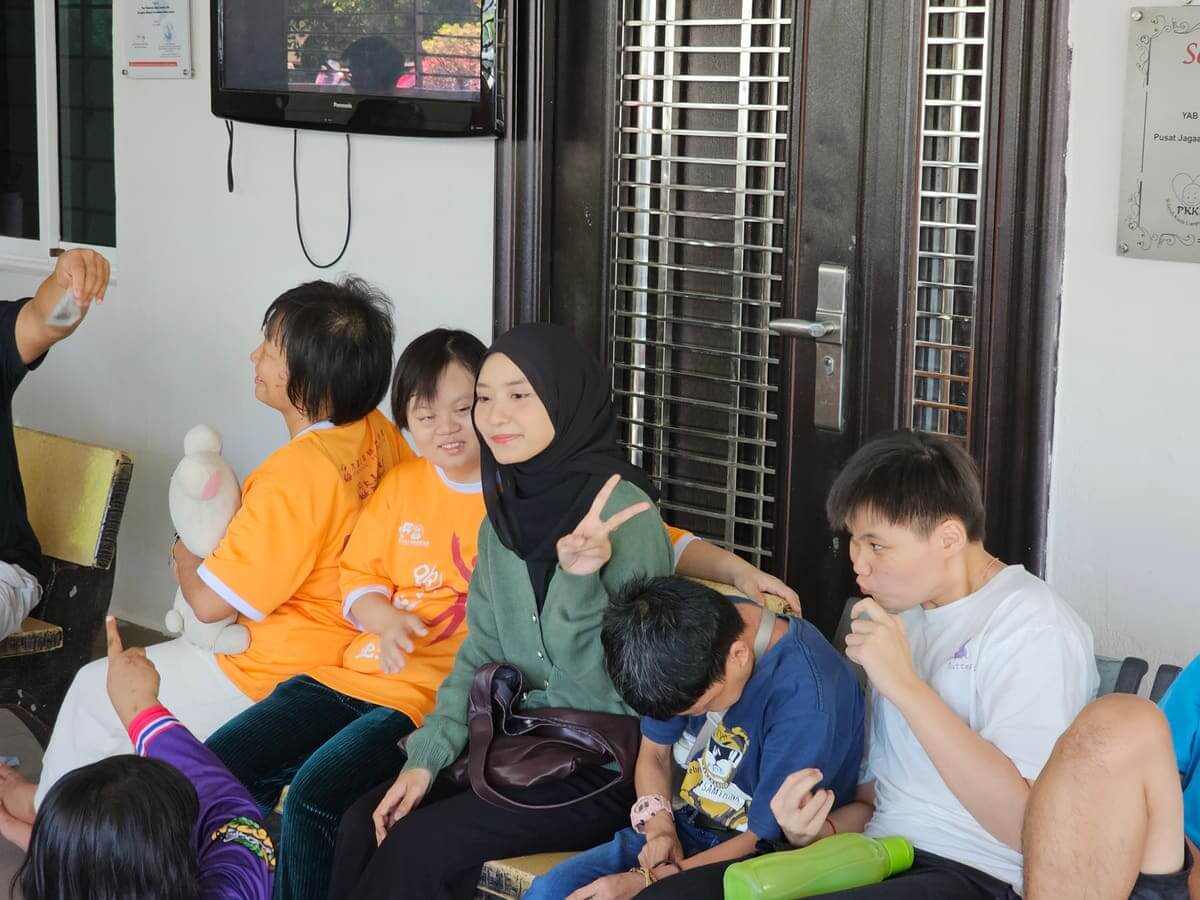 Residents and MedicalMet volunteers circling red plastic chairs during a musical chairs game at the PKKII Insan home in Happy Garden, Kuala Lumpur