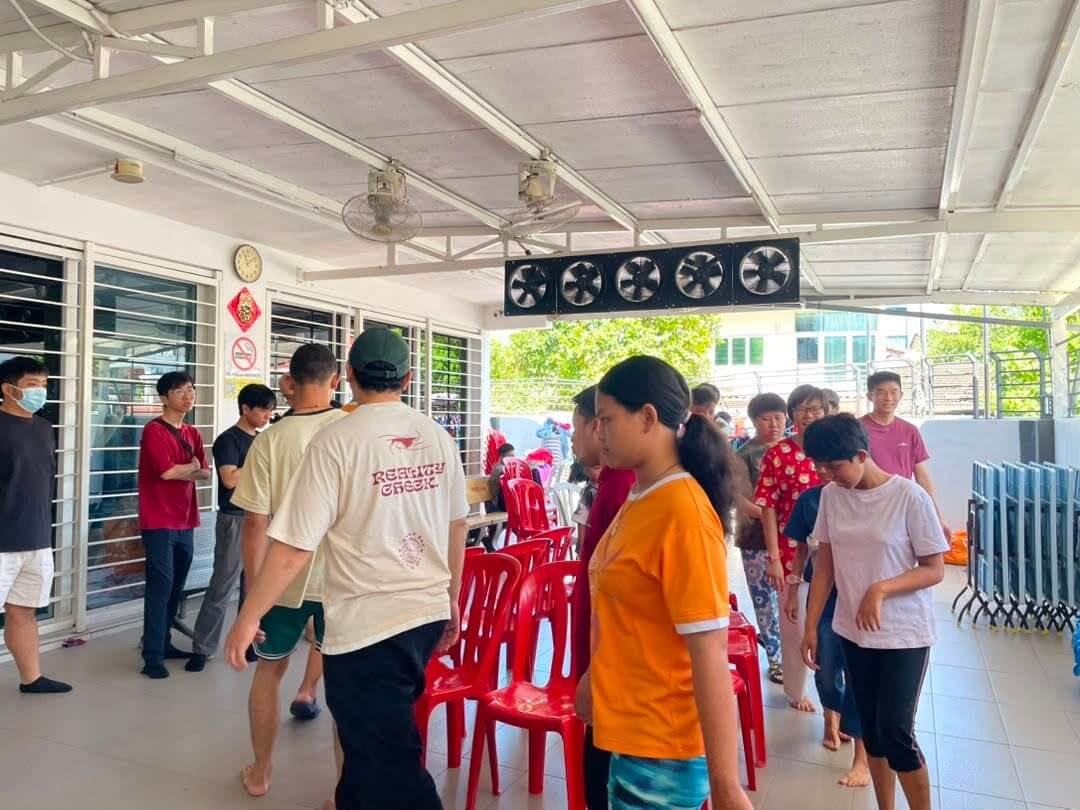 A MedicalMet volunteer sitting on a bench chatting with residents at the PKKII Insan home in Happy Garden, Kuala Lumpur