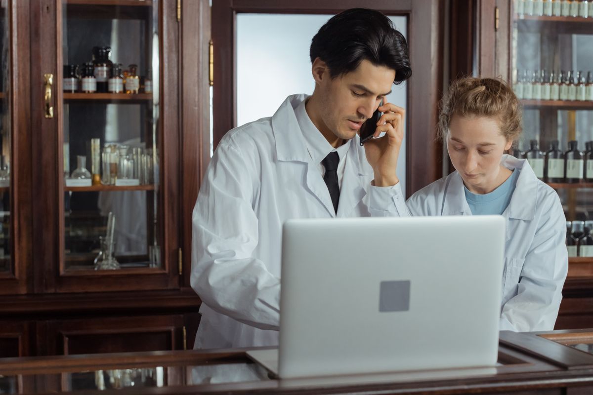 Two pharmacists checking stock levels on a laptop in a dispensary — MedicalMet AI Smart Inventory and purchase orders
