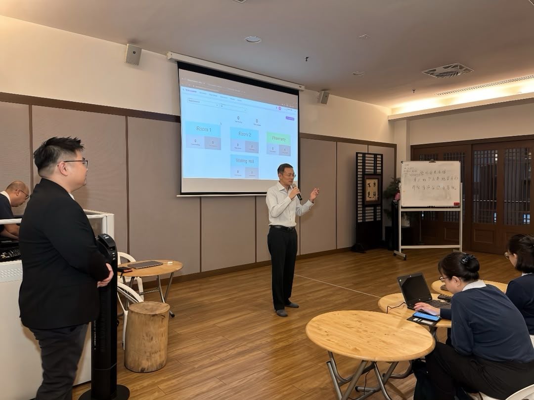 MedicalMet queue board showing Room 1, Room 2, Pharmacy and Waiting Hall on screen during the Tzu Chi International Medical Association session at Jing Si Hall, Kuala Lumpur — MedicalMet