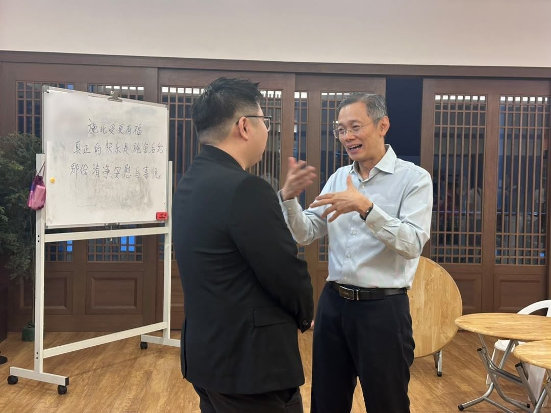 Conversation beside a whiteboard with a Chinese quote during the MedicalMet training session for Tzu Chi International Medical Association volunteers at Jing Si Hall, Kuala Lumpur — MedicalMet